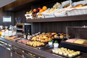 una línea buffet con pan, bollería y otros alimentos en B&B HOTEL Granada, en Pulianas