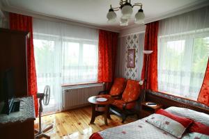 グダニスクにあるAbWentur Pokojeの赤いカーテン、ベッド1台、椅子が備わるベッドルーム1室が備わります。