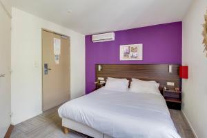 - une chambre avec un grand lit et un mur pourpre dans l'établissement Hotel Le Mistral, à Cannes