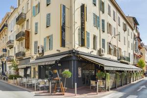 a building with tables and chairs on a street at Hotel Le Mistral in Cannes