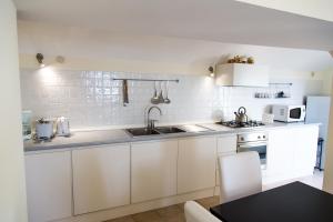 una cocina con armarios blancos y fregadero en Villa Knight, en Amalfi