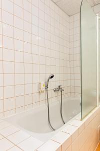a bath tub with a shower in a tiled bathroom at Hotel Rieger Garni in Jičín