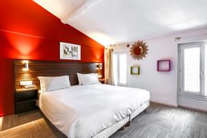 sypialnia z dużym łóżkiem z czerwoną ścianą w obiekcie Hotel Le Mistral w Cannes
