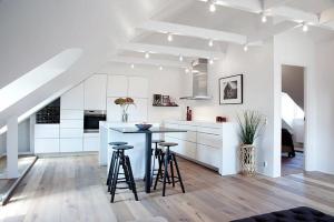a kitchen with white cabinets and bar stools in it at Wow Apartments Örgryte in Gothenburg