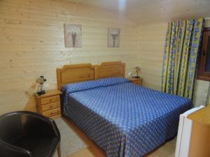 sypialnia z niebieskim łóżkiem i drewnianą ścianą w obiekcie Hostal Gran Avenida w mieście Tarancón