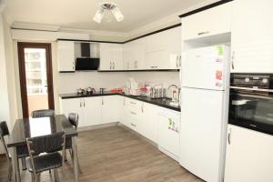 a kitchen with white appliances and a table and chairs at Royal Inn Seza Residence in Trabzon