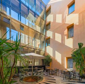 Un patio con mesas y sillas frente a un edificio. en H10 Raco del Pi, en Barcelona