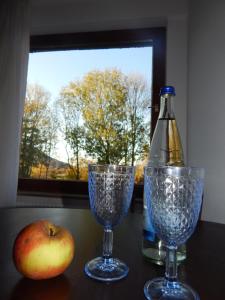 an apple and a bottle and two glasses on a table at FREE Apartment - Bei den Thermen in Bad Urach