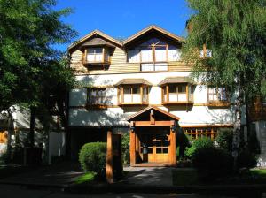 a large white building with a wooden door at Hostería El Arbol Duende in San Martín de los Andes