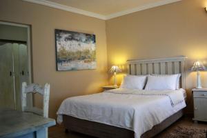 a bedroom with a bed with white sheets and two lamps at Claire's in Ballito
