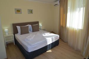 Un dormitorio con una cama con sábanas blancas y una ventana. en Luxury Apartments, en Burgas