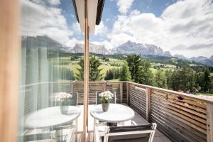 a balcony with two tables and a view of mountains at Alpine Hotel Ciasa Lara in La Villa