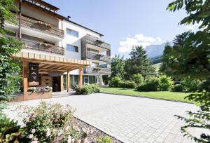 a large building with a courtyard in front of it at Alpine Hotel Ciasa Lara in La Villa