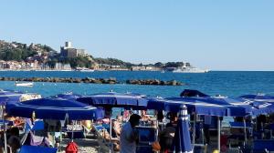 a group of blue umbrellas on a beach with the water at La casetta dei Marinai in Lerici