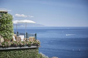 a balcony with chairs and an umbrella and the ocean at Splendido, A Belmond Hotel, Portofino in Portofino