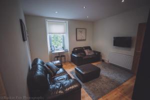 uma sala de estar com um sofá de couro e uma cadeira em Apartment C em Aberdeen