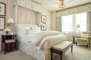 um quarto com uma grande cama branca e uma cadeira em The Hay - Adams em Washington