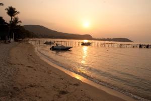a beach with two boats in the water at sunset at Marina Residence in Bang Rak Beach