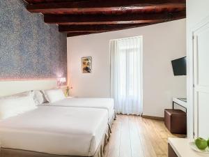 two beds in a hotel room with white walls at H10 Raco del Pi in Barcelona