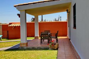 un patio con mesa y sillas bajo una pérgola en Chalet Cala de Roche, en Roche