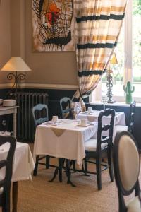 a dining room with two tables and chairs and a window at Hôtel du Parc in Montélimar