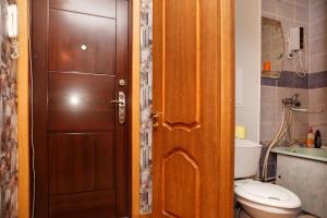 a bathroom with a toilet and a wooden door at Apartment on Krasnoarmeyskaya 137 in Kemerovo