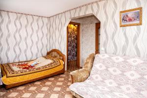 a bedroom with two beds and a chair at Apartment on Krasnoarmeyskaya 137 in Kemerovo