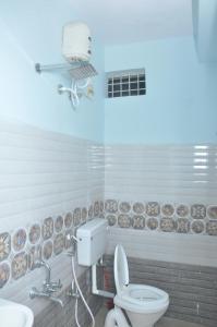La salle de bains blanche est pourvue de toilettes et d'une caméra. dans l'établissement SriPaadha Inn Kanipakam, à Kanipakam