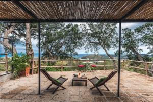 a patio with chairs and a table and a view of the ocean at Borgo degli Ulivi in Porto Ercole