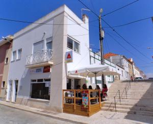 personas sentadas bajo un paraguas fuera de un edificio en Amoreiras, en Peniche