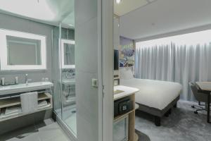 a bathroom with a bed and a sink and a mirror at Arena Hotel La Defense in Nanterre