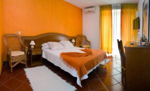 a bedroom with a bed with an orange wall at Solar dos Marcos Rural Accommodation in Bemposta