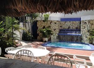 una piscina con una mesa, sillas y una fuente en Hotel Caribe, en Santa Cruz de Barahona