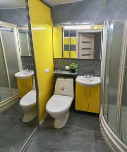 a yellow bathroom with two toilets and a sink at Luxury 2 Rooms Apartments in Center by Green House in Poltava +12 photos