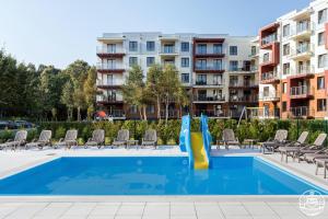 a swimming pool with a slide in front of apartment buildings at Park Design - Apartments M&M (Polanki Park) in Kołobrzeg