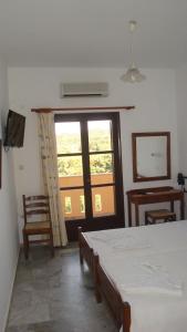 1 dormitorio con cama y ventana grande en Calamon Apartments, en Episkopí- Rethimno