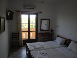 a hotel room with two beds and a window at Calamon Apartments in Episkopí- Rethimno