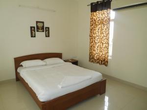 Schlafzimmer mit einem Bett und einem Fenster in der Unterkunft Tulip Serviced Villa in Chennai