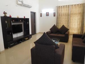 Sala de estar con 2 sofás y TV en Tulip Serviced Villa en Chennai