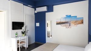 マリーナ・ディ・チェーチナにあるHotel della Contradaの青い壁のベッドルーム1室、ベッド1台、デスクが備わります。