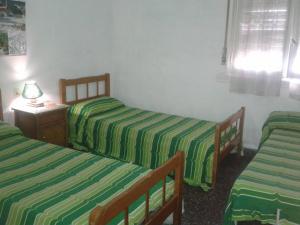 2 camas en una habitación con sábanas de rayas verdes en Casa Vacacional Los Nietos en Quequén