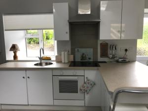 a kitchen with white cabinets and a sink at Hobbit Hollow in Ballymore Eustace