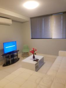 uma sala de estar com uma televisão, um sofá e uma mesa em 77 On Independence Apartments em Windhoek