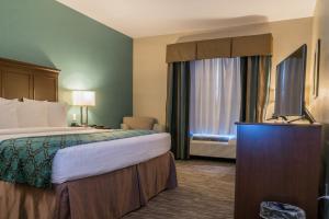 a hotel room with a bed and a flat screen tv at Heritage Place Hotel and Suites in DeQuincy
