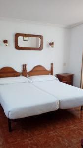 a bedroom with two white beds and a mirror at Hotel Los Perales in Puebla de Sanabria