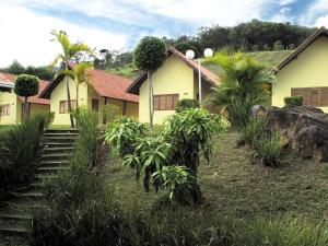 una casa amarilla con palmeras delante en Resort Monte das Oliveiras en Joanópolis