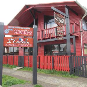 un edificio rojo con señales delante en Cabanas L'ESCALE en Coñaripe