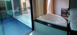 a bathroom with a tub and a swimming pool at Status Motel Perimetral Adults Only in Olinda +3 photos