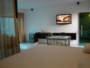 a living room with a table and a tv on the wall at Status Motel Perimetral Adults Only in Olinda