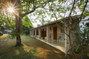 Una casa blanca con un árbol delante. en Pousada Vento Sul en Chapada dos Guimarães